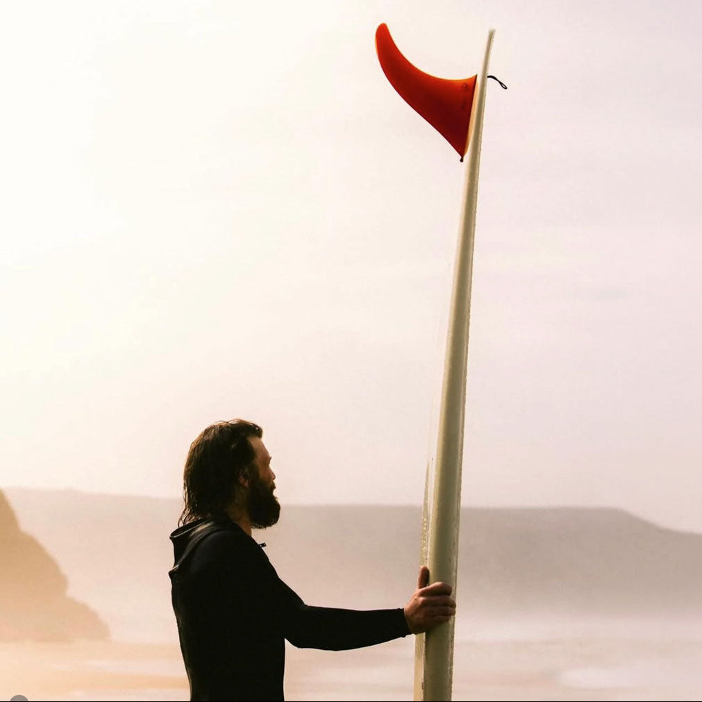 Surfer holding a surfboard with a red Flying Diamond Fin