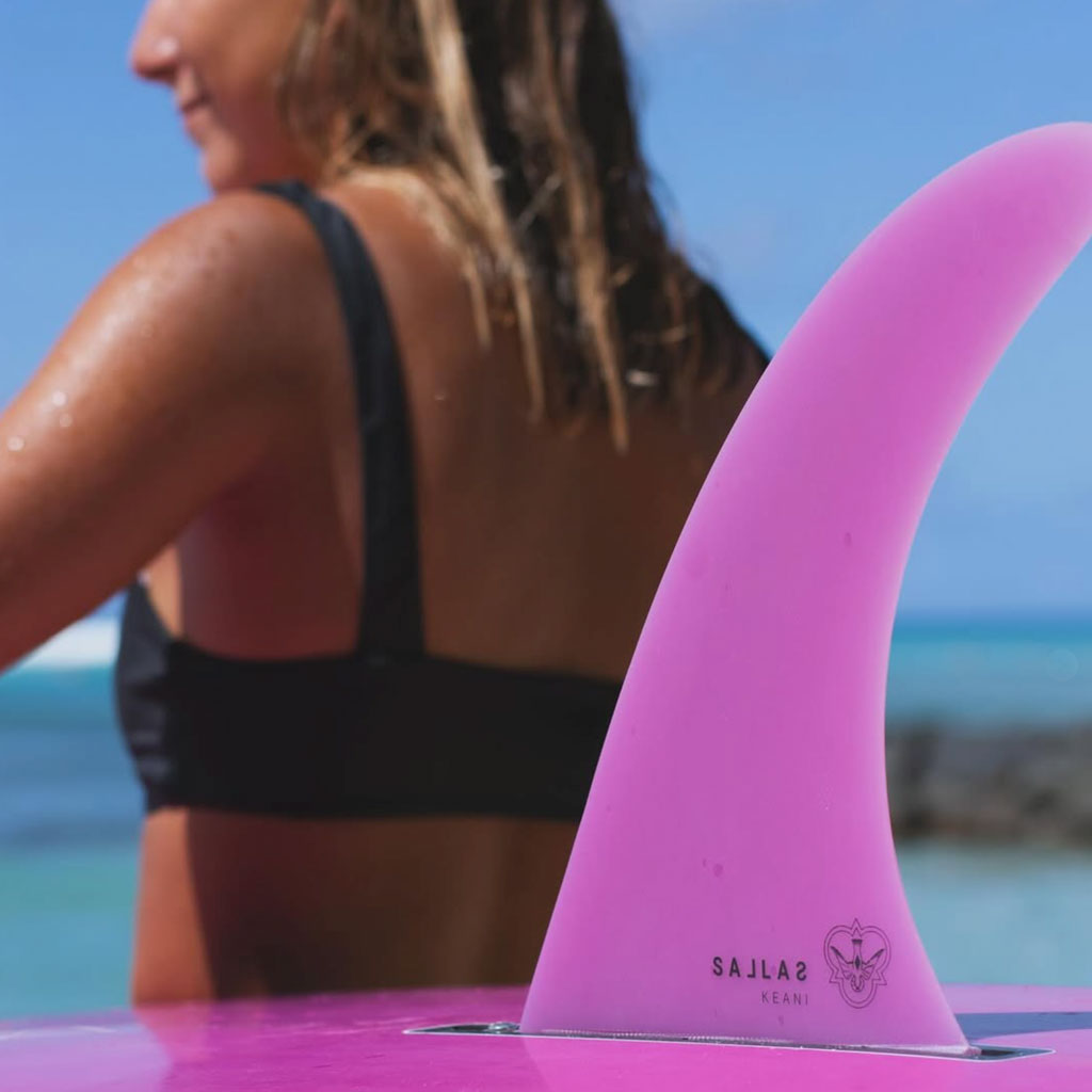 Surfer holding a surfboard with a Pink Flying Diamond Fin