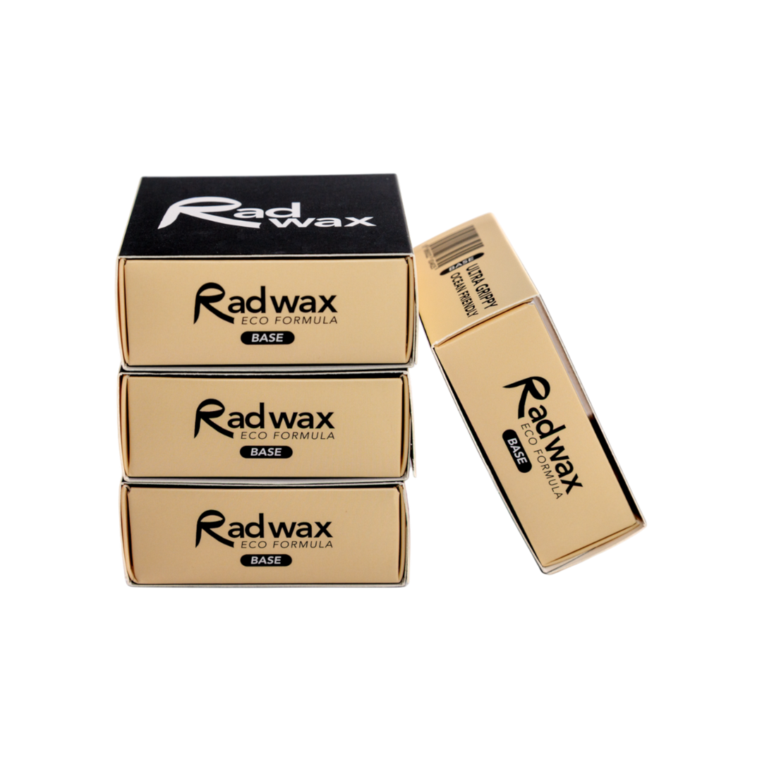 Three gold and black boxes of Radwax Iso Formula Base wax are arranged on a plain white background, with one box standing upright next to the stacked boxes.