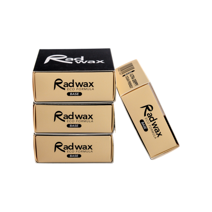 Three gold and black boxes of Radwax Iso Formula Base wax are arranged on a plain white background, with one box standing upright next to the stacked boxes.
