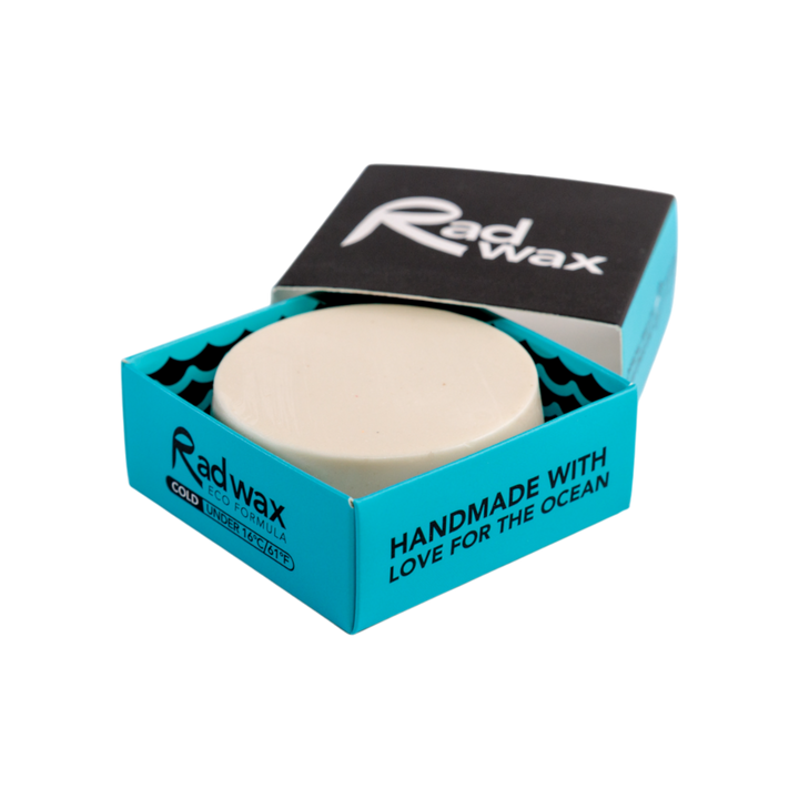 A round beige wax melt by Radwax, presented in its open turquoise and black cardboard packaging on a solid white background.