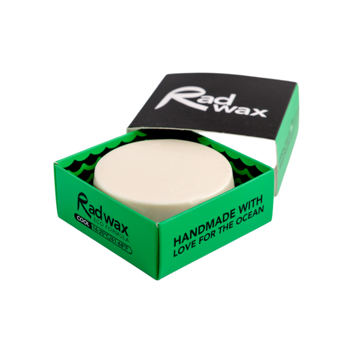 A round beige wax bar displayed in an open green and black Radwax box on a plain white background.